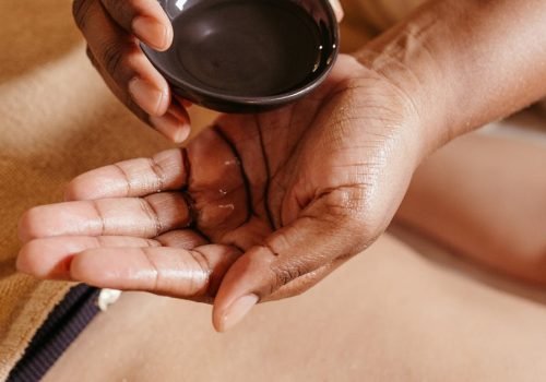 Hands applying massage oil on a client's back in a spa setting for relaxation and rejuvenation.