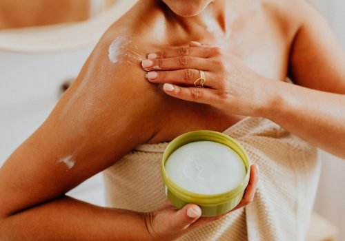Close-up of a woman applying cream to her shoulder, focusing on skincare and self-care routines.