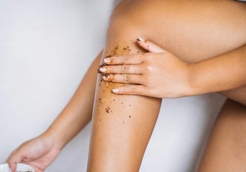 Woman applying exfoliating scrub to her leg for smooth skin care.
